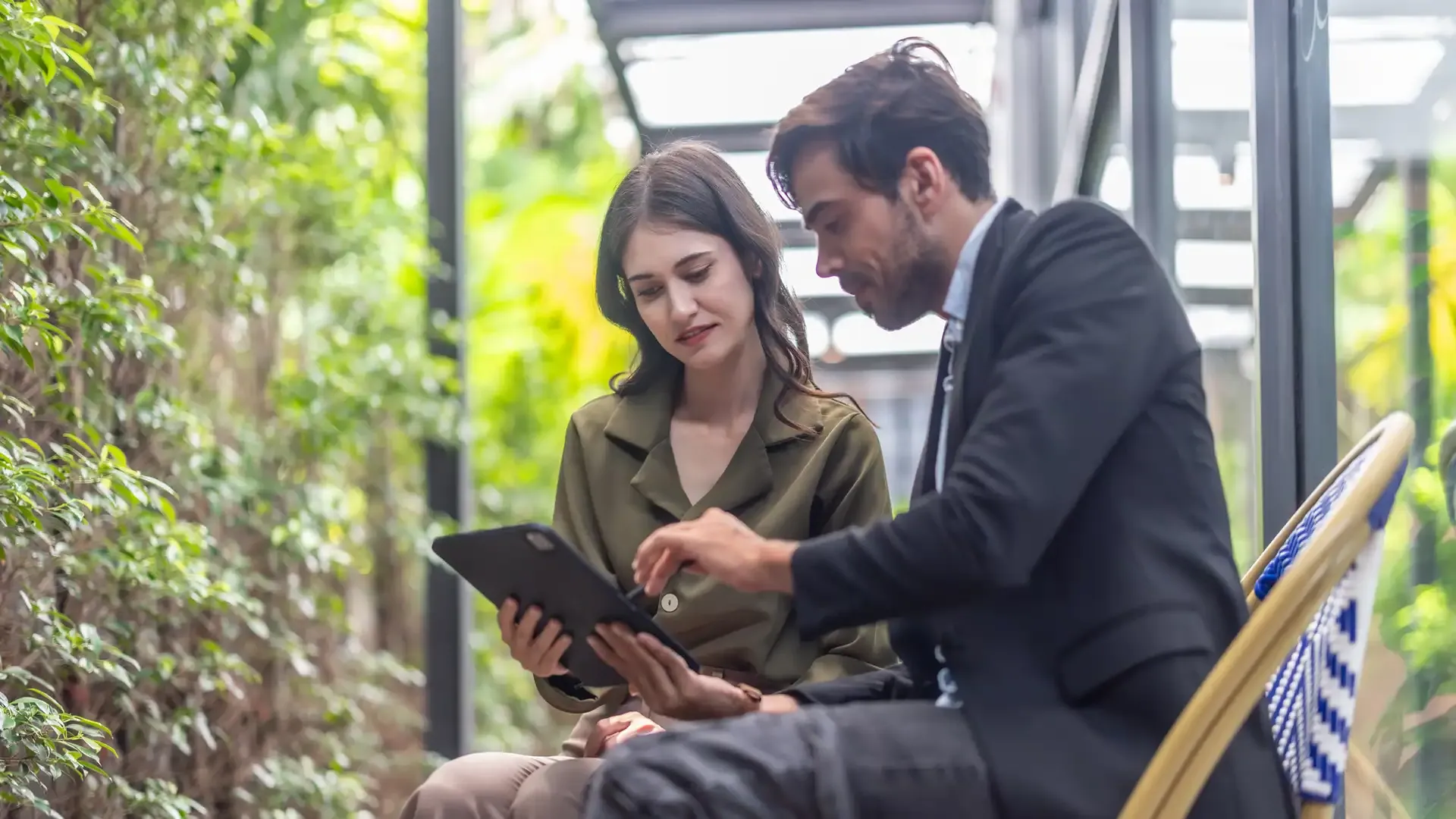 Two colleagues reviewing statistical information in a leafy environment